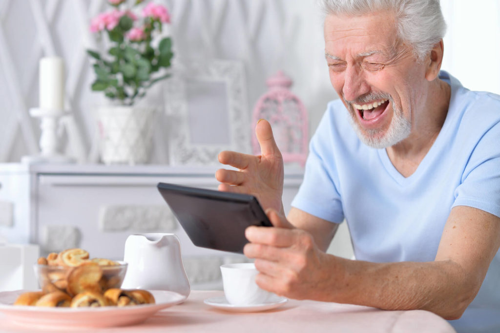 Older man happily using a tablet.