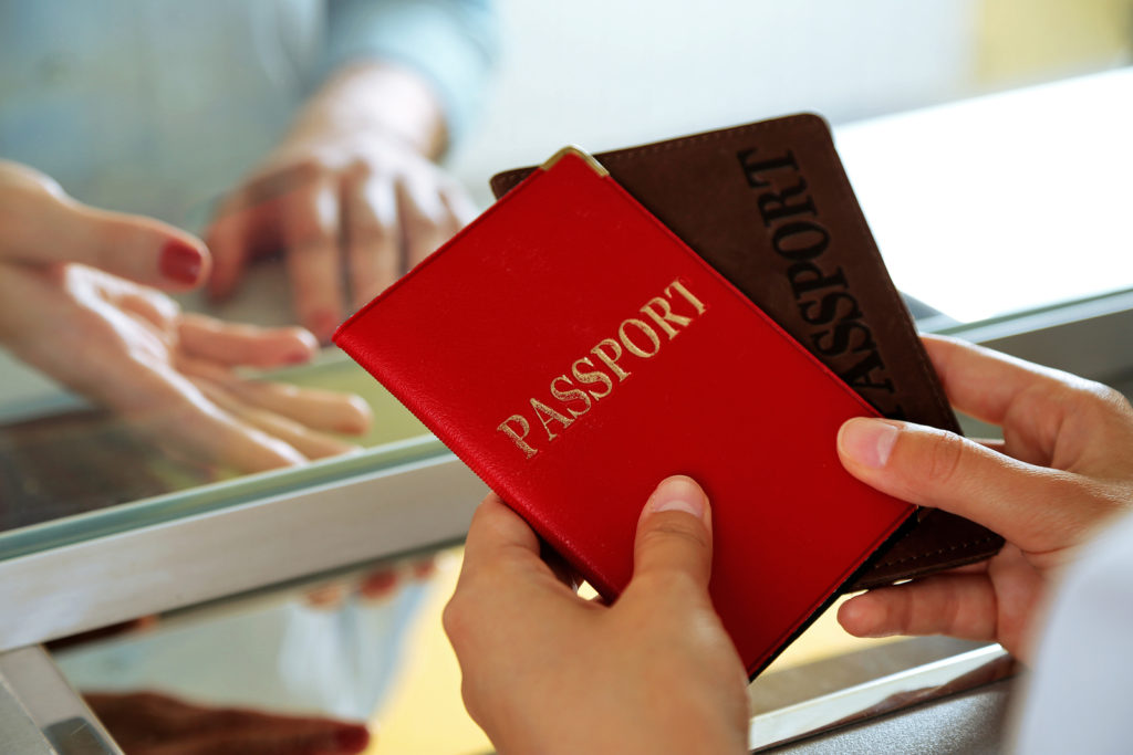 Image shows a a red passport in hands.
