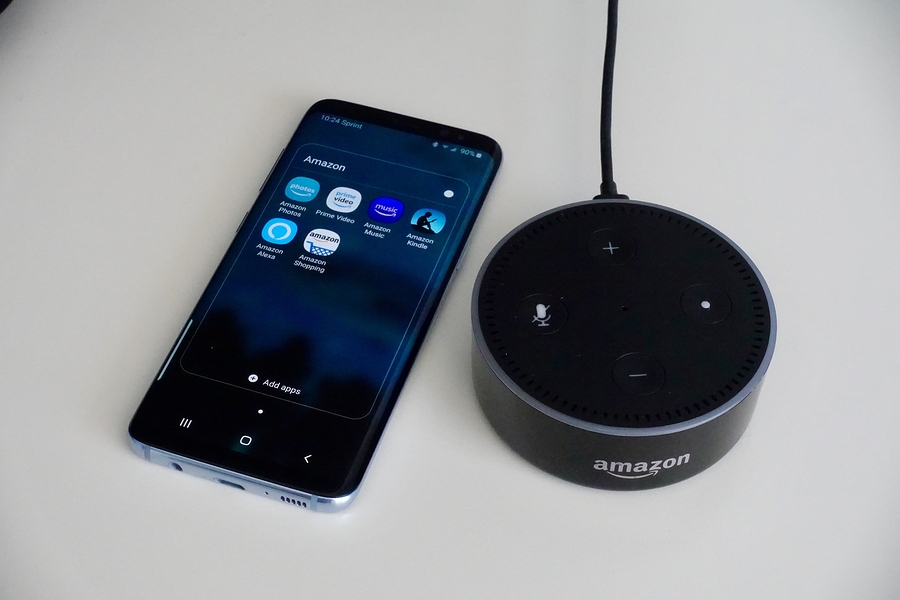 Amazon Alexa speaker next to smart phone with Amazon apps
