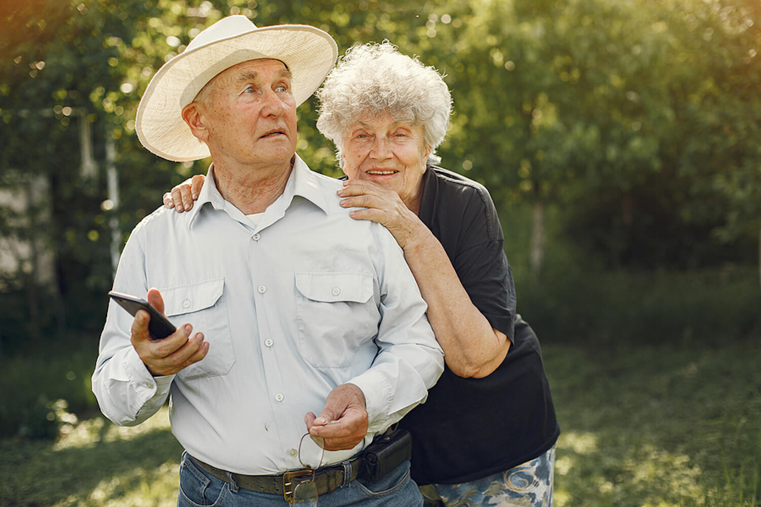 Image shows beautiful older couple enjoying a walk in summer greenery.