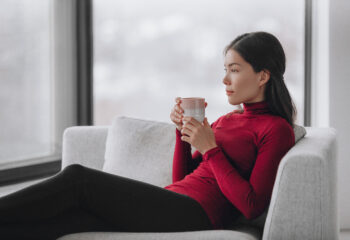 Image shows serene woman relaxing with a cup of tea.