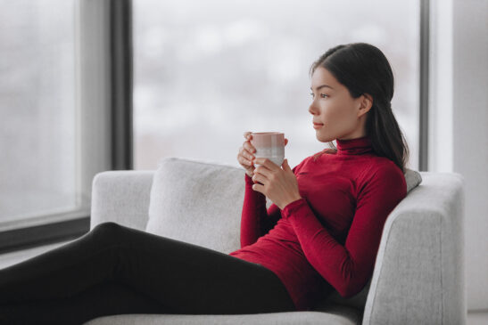 Image shows serene woman relaxing with a cup of tea.