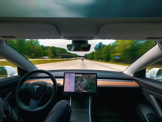 Image shows person driving Tesla on Autopilot.