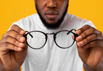 Image shows man holding eyeglasses that no longer correct his vision impairment.