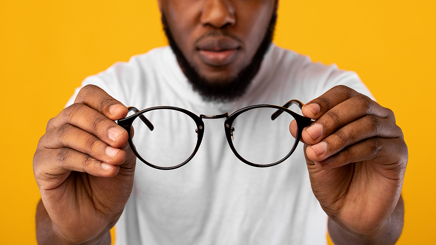 Image shows man holding eyeglasses that no longer correct his vision impairment.