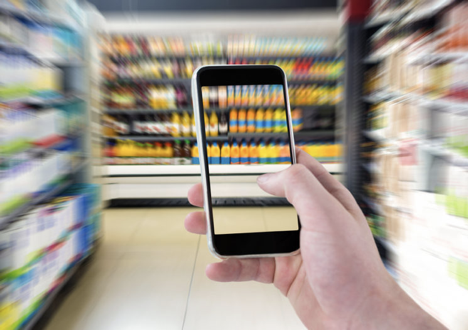 Image shows hand holding smartphone while using Aira app in supermarket