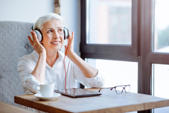Cheerful woman with headphones listening to audiobook.