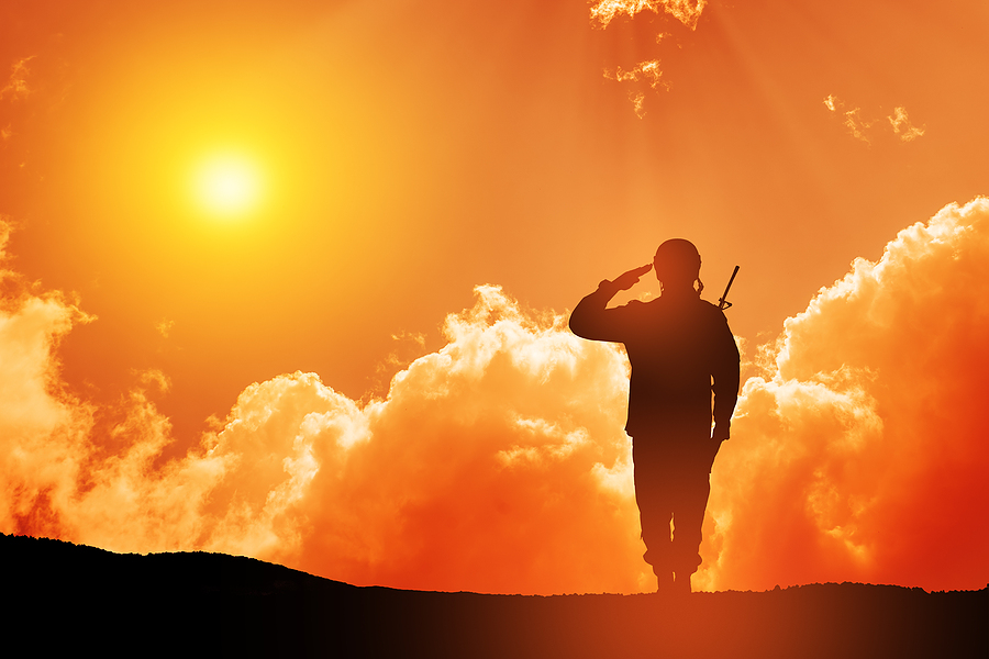 Memorial image of soldier saluting with sunset in the background. 