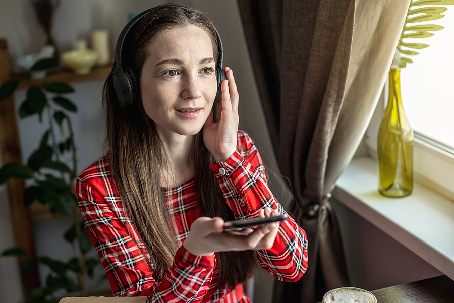 A woman joyfully listening to audiobook from smartphone.
