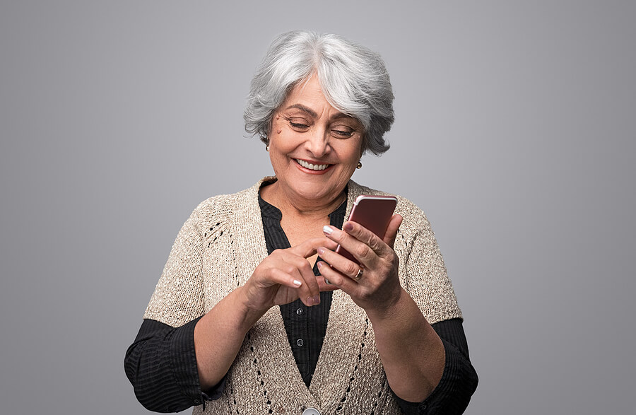 Savvy senior woman happily using smartphone.