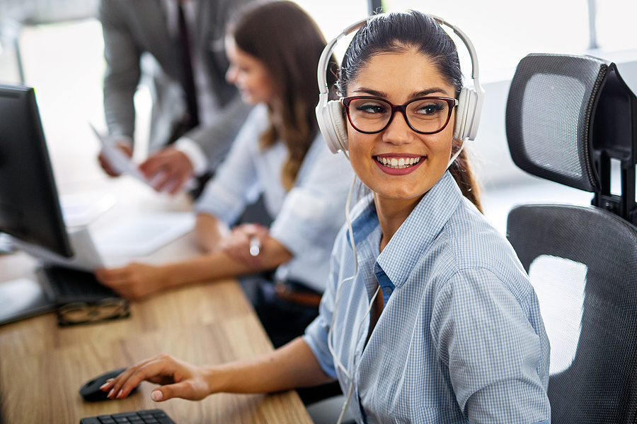 Smiling friendly call-center agent with headset working on support phone line