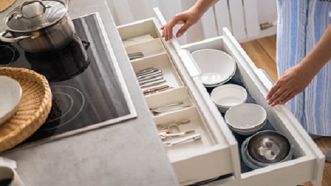 Hands reaching into well organized kitchen drawer