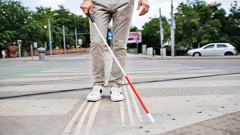 Visually impaired person with white cane crossing
 city street