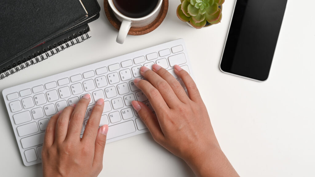 Woman’s hands typing on Mac keyboard