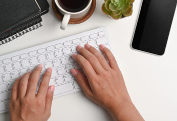 Woman’s hands typing on Mac keyboard