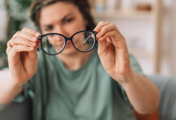 Person holds glasses away from eyes to refocus