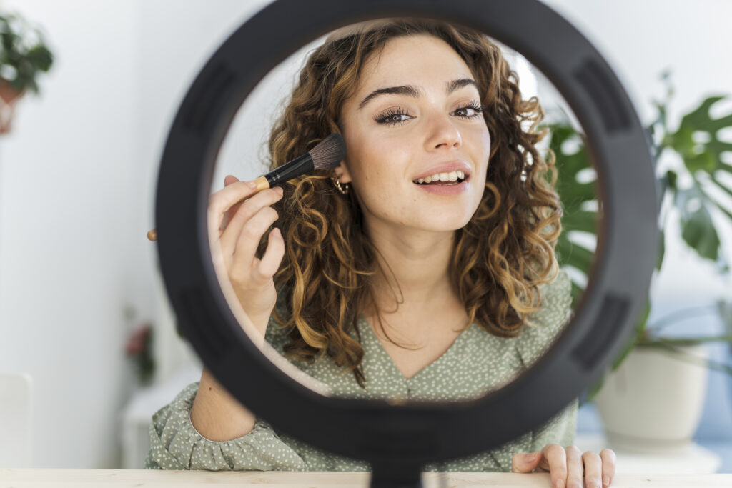 Woman applying makeup in mirror with light
