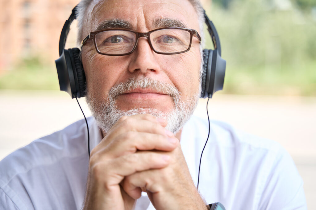 Older adult man listens intently to audio magazine