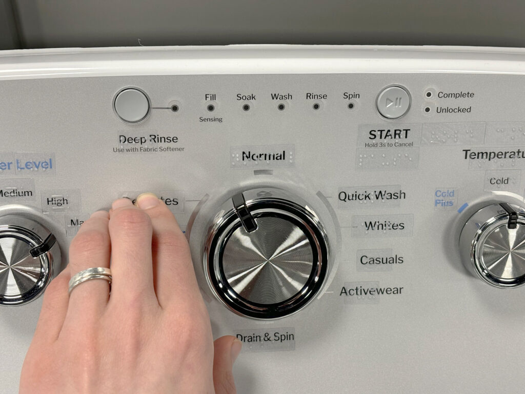 Hand touching tactile stickers on GE washer