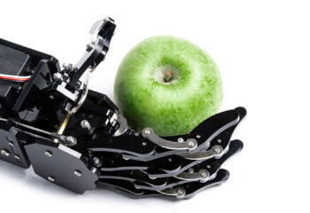 A robotic hand holding green apple is symbolic of Apple Intelligence